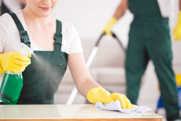 Close-up of cleaning lady spraying the table with green detergent